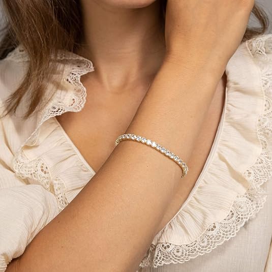 Close-up of a person wearing a delicate bracelet with a white lace top.