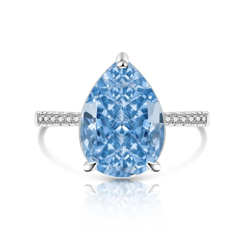 Pear-shaped blue diamond ring with a white gold band on a white background