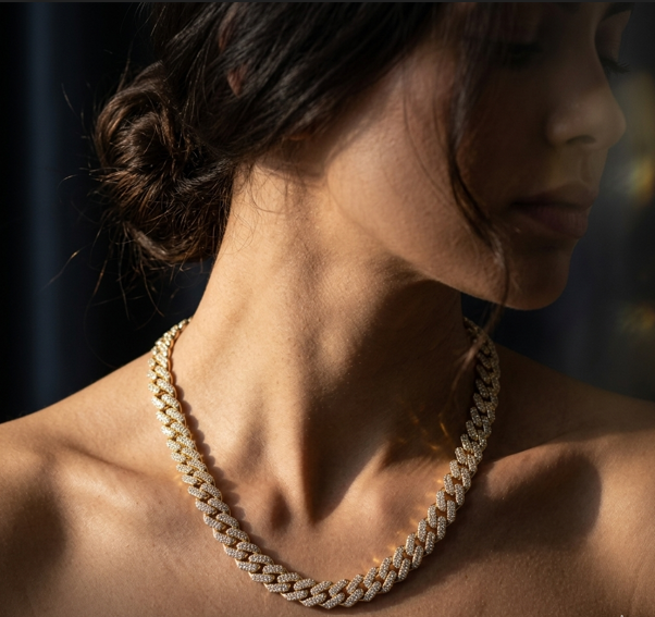 Close-up of a person wearing a gold chain necklace with a blurred background