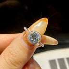Silver ring with a diamond held between fingers against a dark background