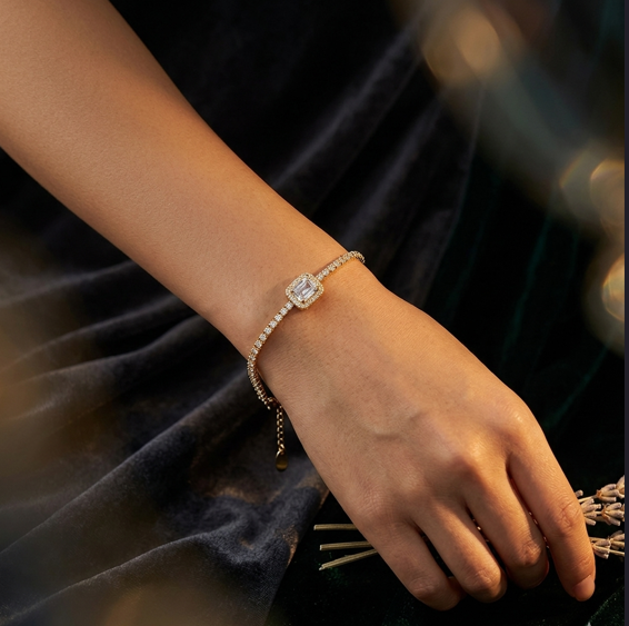 Close-up of a hand wearing a diamond bracelet on a dark background