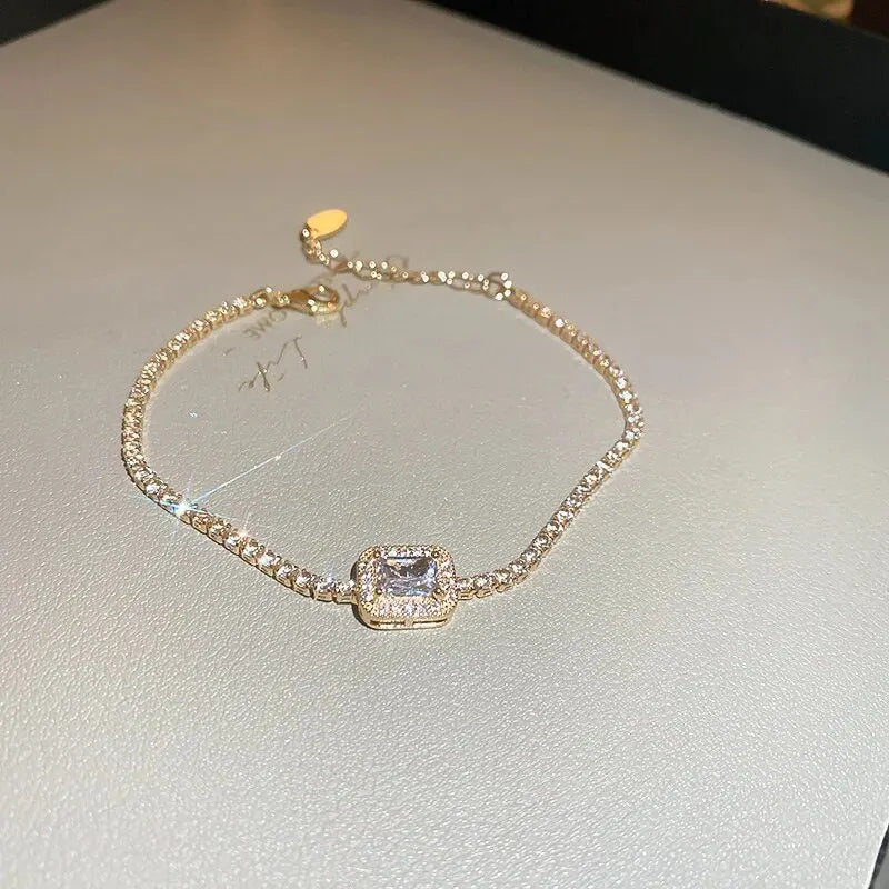 Gold bracelet with a central gemstone on a light gray surface