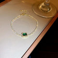 Bracelet with a green gemstone on a reflective surface