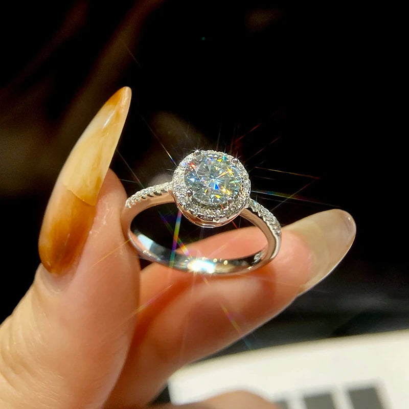 Silver ring with a large diamond held by a hand against a blurred background