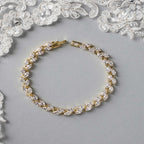 Gold and crystal bracelet on a gray surface with lace in the background