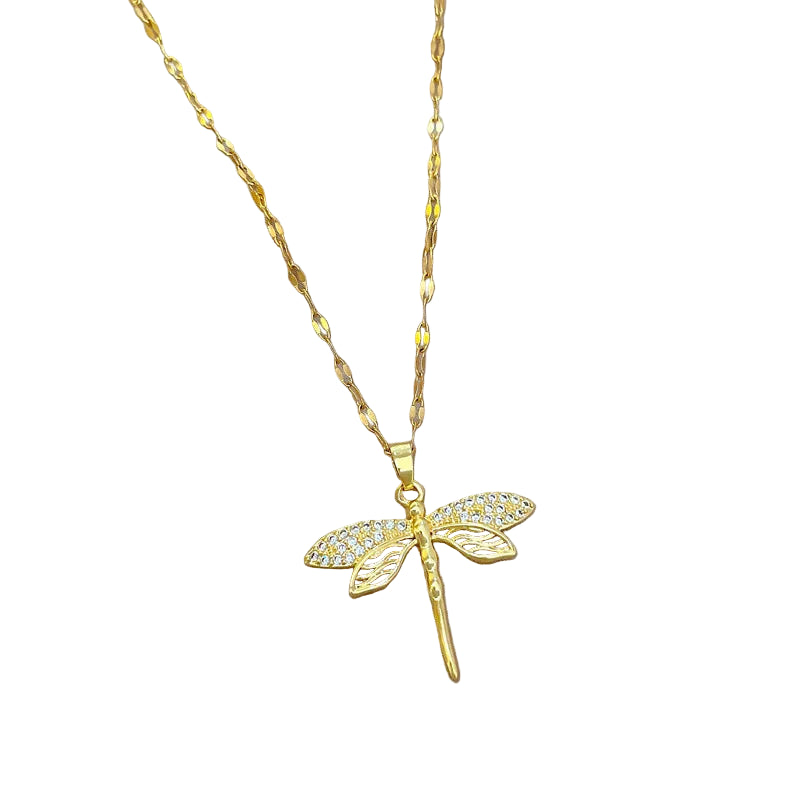 Gold dragonfly pendant necklace on a soft fabric background