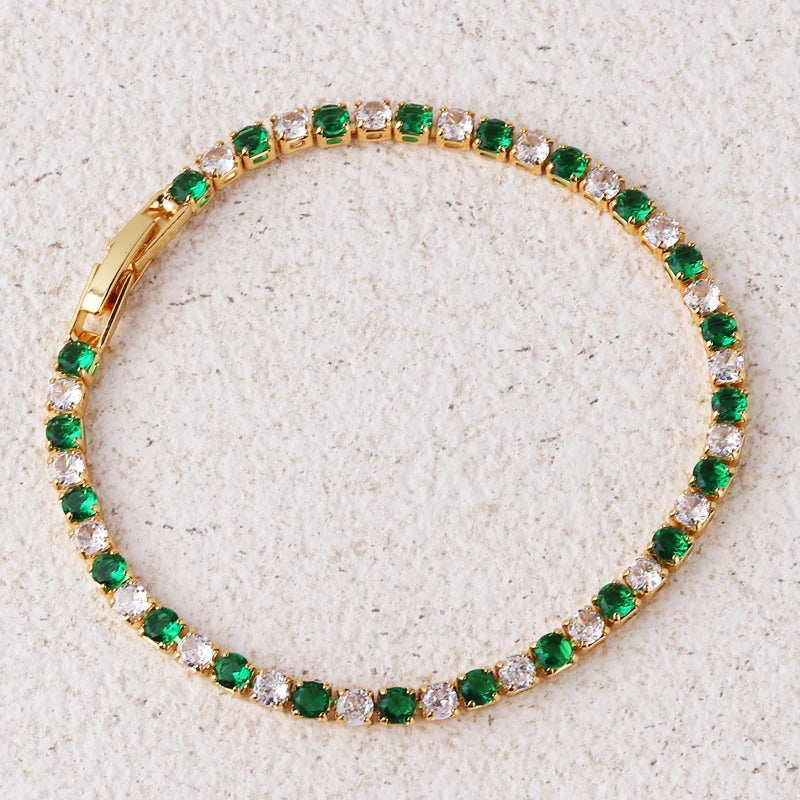 Gold bracelet with green and clear gemstones on a textured beige background