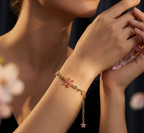 Close-up of a person wearing a delicate bracelet with floral designs against a blurred background.