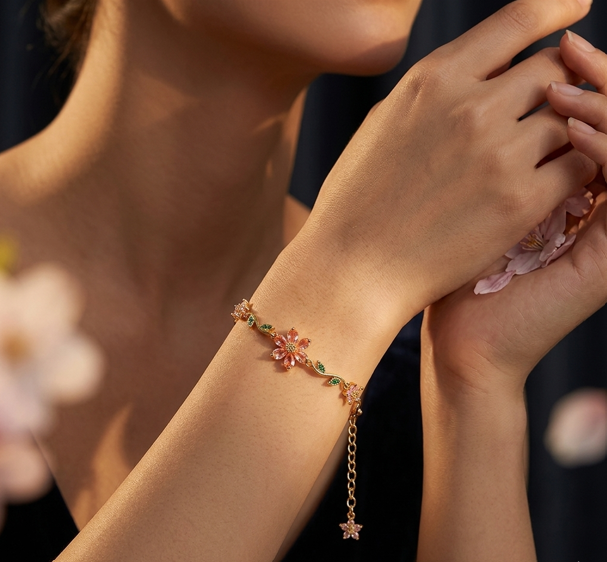 Close-up of a person wearing a delicate bracelet with floral designs against a blurred background.