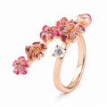 Rose gold ring with pink gemstones and a central diamond on a white background
