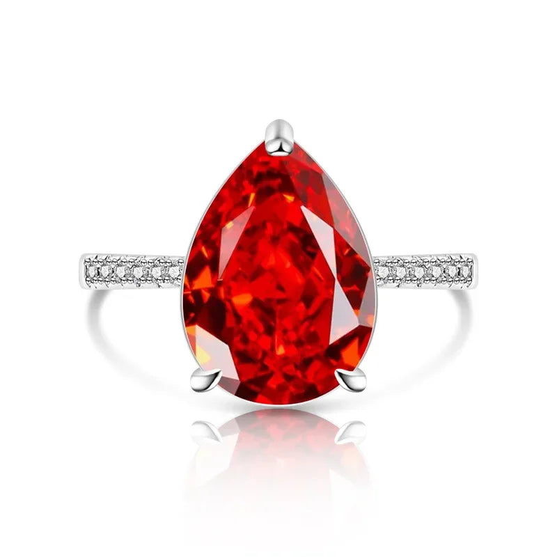 Ring with a large red gemstone and smaller diamonds on a white background