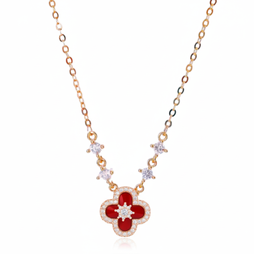 Gold necklace with a red clover-shaped pendant on a white background