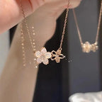 Floral necklace with a chain held by a hand against a blurred background