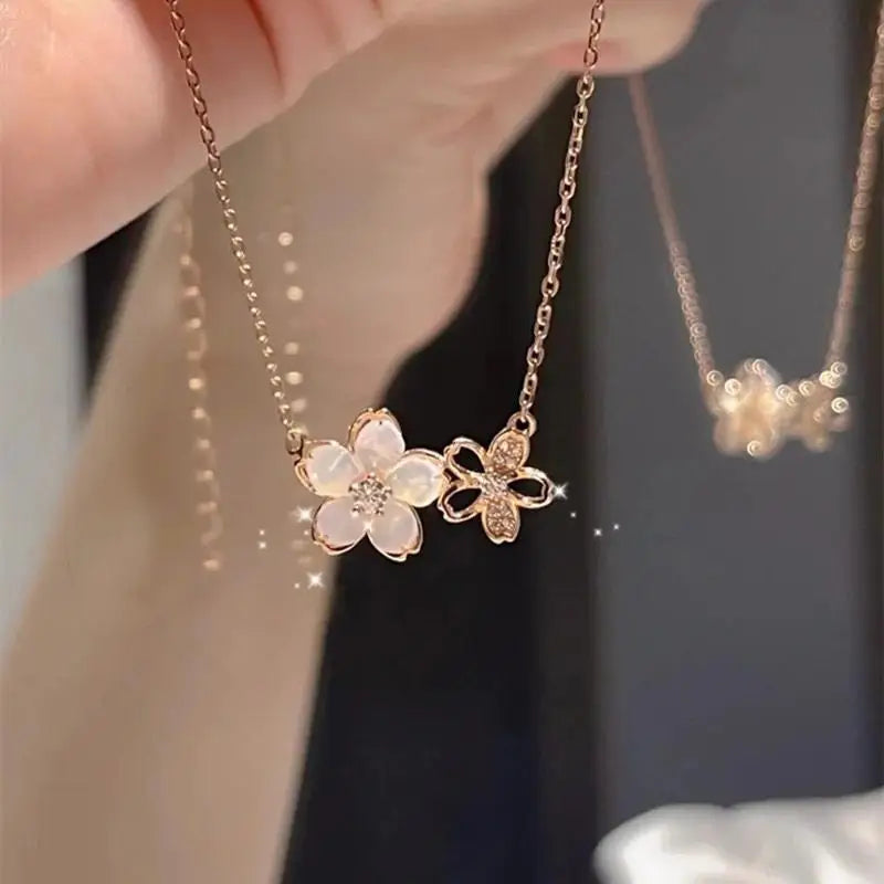 Floral necklace with a chain held by a hand against a blurred background
