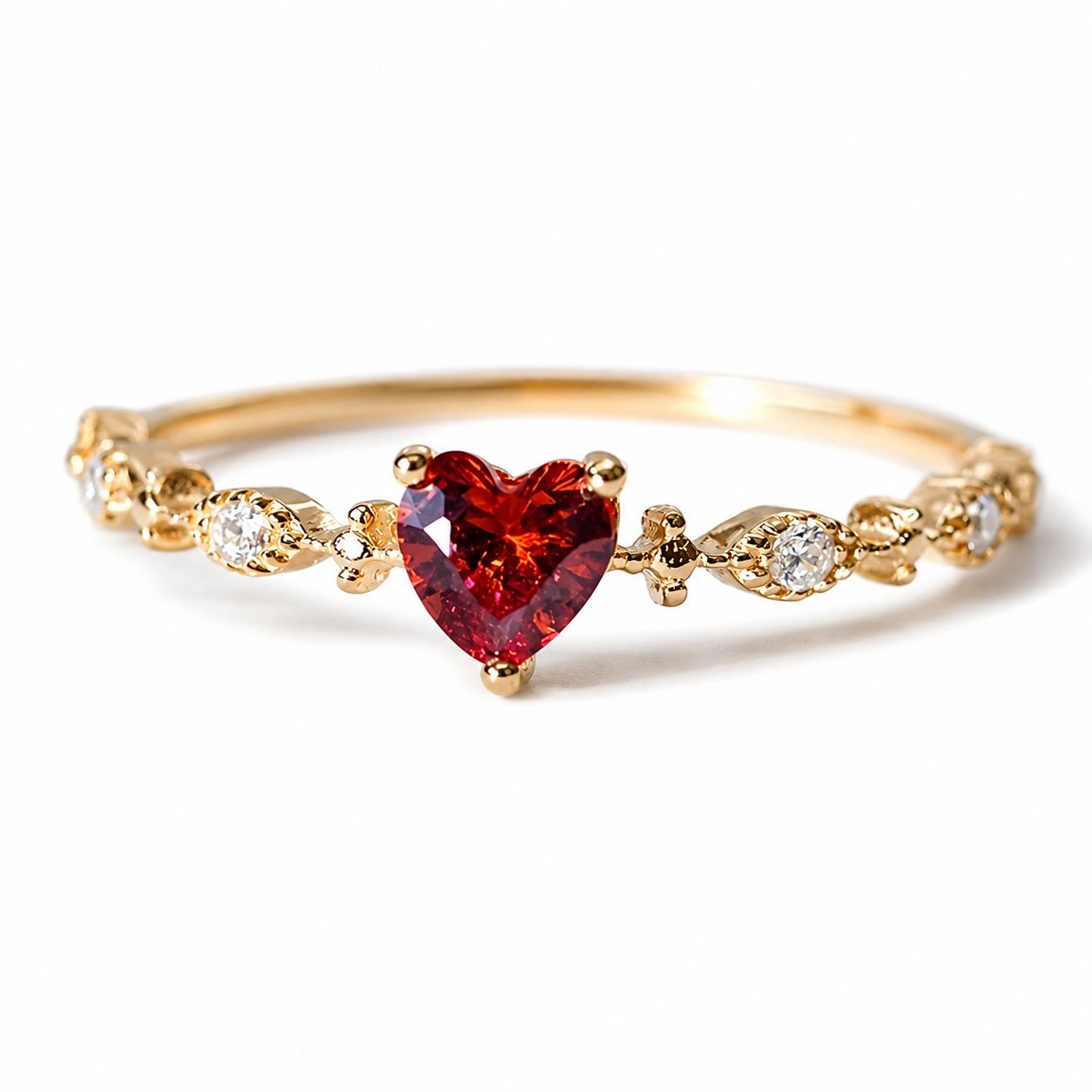Gold ring with a heart-shaped red gemstone on a white background