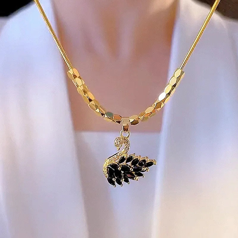 Gold necklace with a black swan pendant on a white background