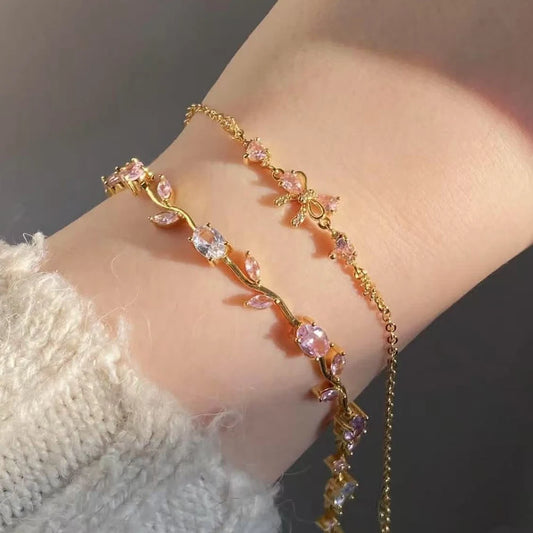 Gold bracelet with pink gemstones on a wrist against a neutral background