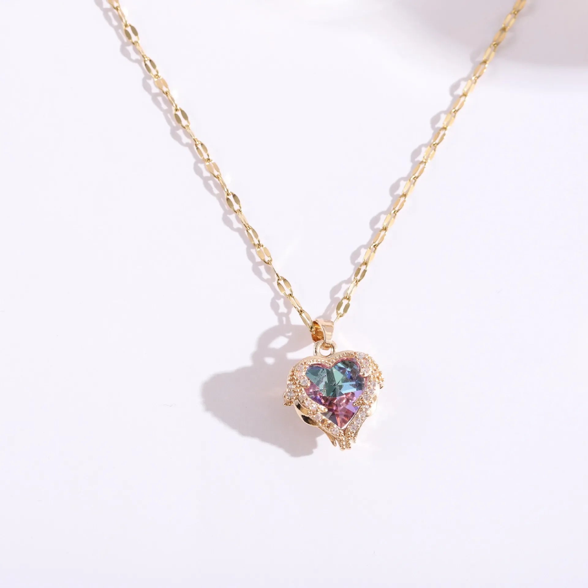 Heart-shaped pendant necklace with a gold chain on a light background
