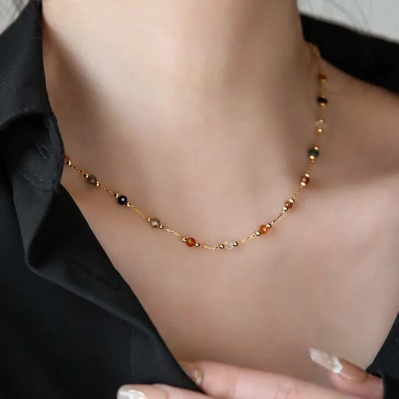 Necklace with multicolored beads worn by a person against a neutral background
