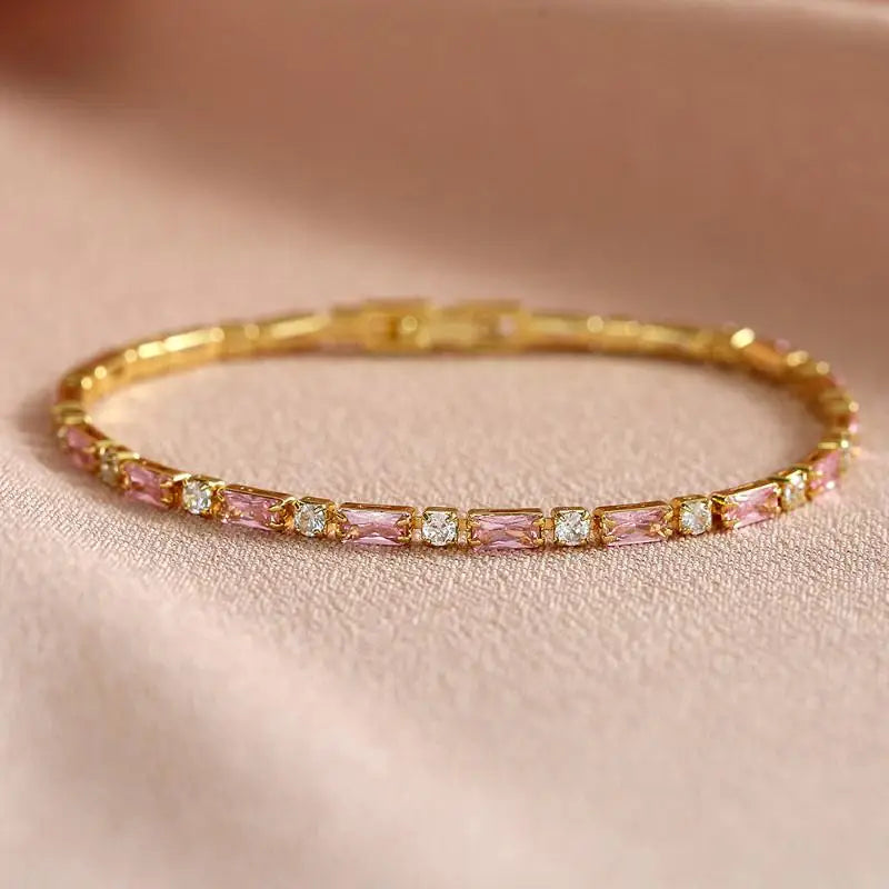 Gold bracelet with pink gemstones on a beige background