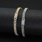 Two diamond-encrusted bracelets, one gold and one silver, on a black surface.