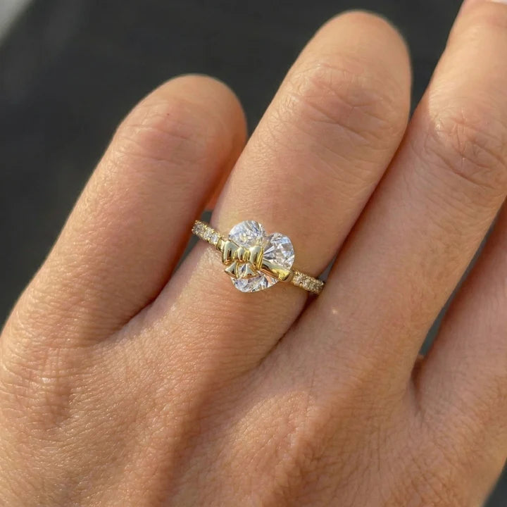 A yellow gold ring with a large clear round-cut center stone and smaller side stones, shown worn on a person's finger.