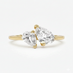 Gold ring with two pear-shaped diamonds on a white background
