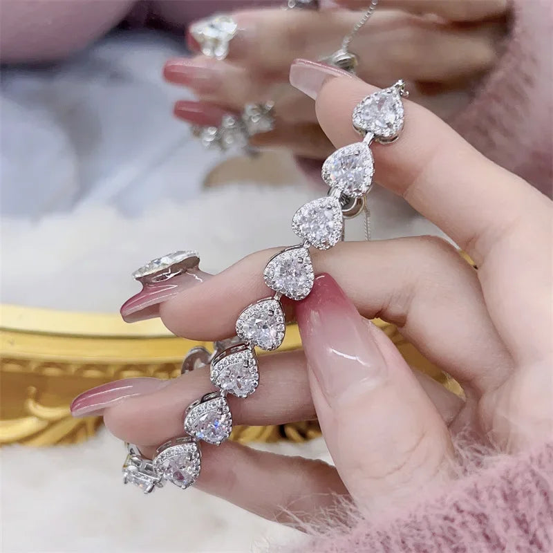 Diamond bracelet held by a hand with a blurred jewelry display in the background