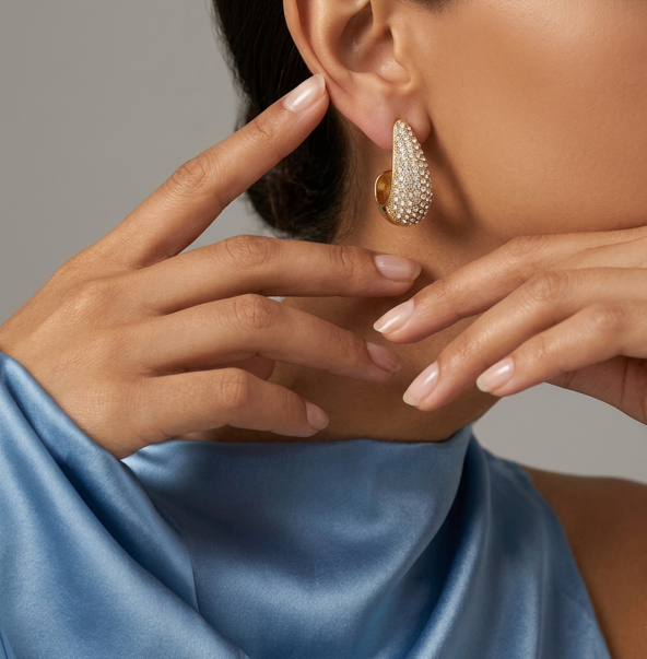 Close-up of a woman wearing a gold earring with a pearl-like finish, against a neutral background.