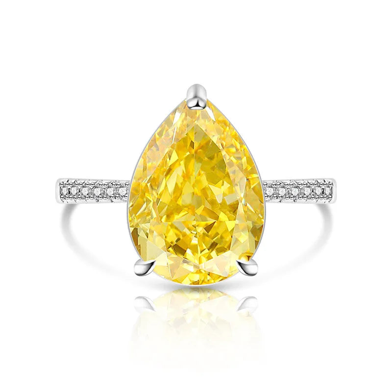 Ring with a large yellow pear-shaped diamond and smaller diamonds on the band against a white background